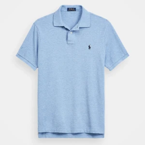 Ljusblå pikétröja från Polo Ralph Lauren - Klassisk ljusblå pikétröja från Polo Ralph Lauren med krage och två knappar framtill. Tröjan har korta ärmar och den ikoniska broderade loggan på bröstet. Perfekt för en stilren och avslappnad look.