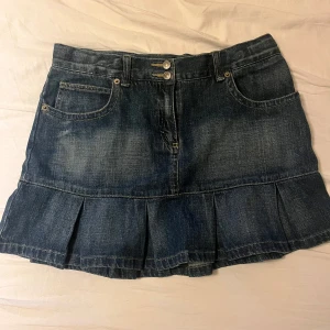  jeanskjol med volang - Säljer en mörkblå jeanskjol med volangkant nedtill. Kjolen har klassiska jeansfickor fram och bälteshällor i midjan. Perfekt för dig som gillar en cool och avslappnad stil.