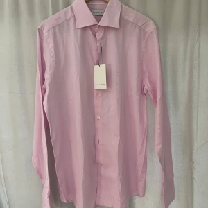 Ljusrosa skjorta från These Glory Days - Säljer en stilren ljusrosa skjorta från These Glory Days. Skjortan har klassisk krage, knäppning framtill och långa ärmar. Perfekt för dig som vill ha en enkel men snygg skjorta, säljer den då den satt åt lite i axlarna annars perfekt!                               Jag som testat den är 195 cm, väger 99kg 