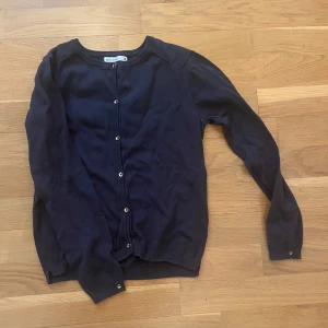 Mörkblå kofta från Zara Girls - Mörkblå kofta från Zara Girls Winter Collection med rund halsringning och guldiga knappar framtill. Klassisk och enkel design som passar till mycket. Mjuk och skön stickad känsla. 