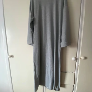 Ljusgrå långklänning i bomull |Abaya - Enkel och stilren ljusgrå långklänning med lång ärm. Klänningen har rak passform och är tillverkad i mjuk bomull, perfekt för en avslappnad look. Storlek S, passar 160cm