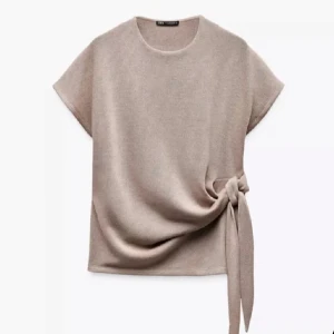 Beige stickad topp med knyt från Zara - Säljer en beige stickad topp från Zara med korta ärmar och snygg knytdetalj i sidan. Använd fåtal gånger och helt nytt skick. Perfekt inför sommaren💗