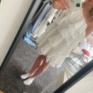 Vit volangklänning med asymmetrisk axel - Säljer denna by malina klänning, helt oanvänd i storlek 38/M.🥰