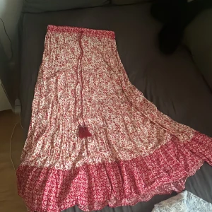 Röd och vit blommig långkjol med volang - Superfin långkjol från Zara. Endast använd 2 gånger så ser ut som ny. Säljs tyvärr då jag tycker den är lite kort till mig för min smak (är 180cm för referens). Den är i storlek M men skulle säga att den fungerar lika bra som S eller L, resårband i magen och flowy i längden. Hör av er om ni är intresserade eller vid frågor