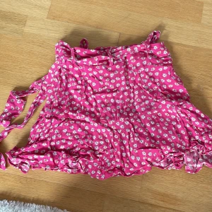 Rosa blommig kjol från Zara - Supersöt rosa kjol från Zara med vitt blommönster och volangdetaljer. Det är inbyggda shorts i kjolen.