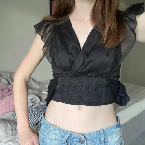 Svart omlottopp  - Intressekoll! (Klicka ej på köp nu) Jättesöt cropped omlottopp som har volanger och knytband i sidan. Storlek XS från veromoda🩷