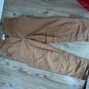 Beiga raka chinos - Säljer ett par beiga chinos med raka ben och normal passform. Byxorna har fickor både fram och bak samt stängs med knapp och dragkedja. Perfekta för en stilren och avslappnad look.