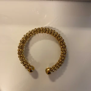 Armband - Säljer ett snyggt guldfärgat armband med pärlliknande detaljer runt hela bandet. 