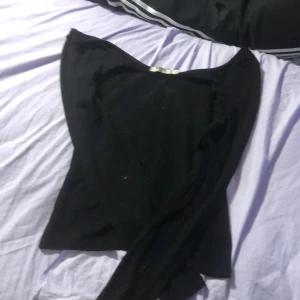 Svart långärmad topp med bred ringning - Säljer en svart långärmad topp med bred, rundad ringning. Toppen är tight i passformen och har en enkel, stilren design utan synliga detaljer eller mönster. Perfekt att styla med jeans eller kjol.