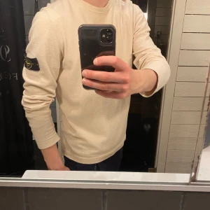 Beige långärmad tröja från Stone Island - Säljer en stilren beige långärmad tröja från Stone Island med klassisk patch. Storlek L, passar även M. Helt äkta. 