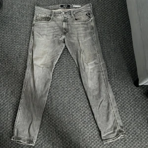 Replay jeans  - Säljer ett par grå jeans från replay med klassisk femficksdesign och raka ben. Byxorna har diskreta slitningar och detaljerade sömmar på bakfickorna. Perfekta för en avslappnad stil.