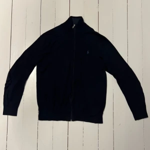 Ralph Lauren Fullzip - Ralph Lauren fullzip i mörkblå, säljes på grund av att den är för liten. Kvitto finns, hör av er vid eventuella frågor!