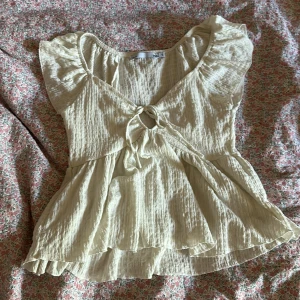 Ljusbeige blus med knyt och volang från lager 157 - Supersöt ljusbeige blus från lager 157 med knyt framtill och lätt volang nedtill. Toppen har korta ärmar som kan bäras offshoulder och är gjord i ett krinklat, luftigt bomullstyg. Perfekt för varma dagar. Kontakta mig om du har några frågor ❤️❤️