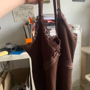 Brun ribbad klänning  - Supersöt brun ribbad kortklänning från H&M Divided i storlek XS. Klänningen har smala axelband, spetsdetaljer vid urringningen och en figurnära passform. Perfekt för dig som gillar en enkel men ändå söt stil.
