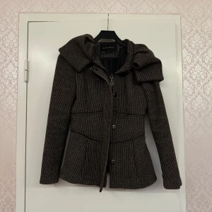 Brun rutig kappa från Zara - Snygg brun rutig kappa från Zara Basic i storlek S. Jackan har markerad midja, bred krage och stängs med både dragkedja och knappar. Perfekt för för vår och höst.
