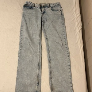 Ljusblå raka jeans i straight fit - Säljer ett par ljusblå jeans med klassisk femficksdesign och raka ben. Jeansen har en straight passform och är tillverkade i denim. Perfekta för dig som gillar en avslappnad och tidlös stil.