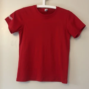 Röd Clique t-shirt Eskilstuna Gymnasterna - Röd t-shirt från Clique med tryck för Eskilstuna Gymnasterna på ryggen och Stadium-logga på ärmen. Klassisk rund hals och korta ärmar. Tillverkad i ett sportigt, lätt material som passar perfekt för träning och gymnastik.