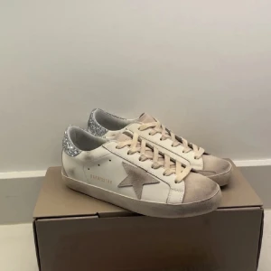 Golden Goose Superstar sneakers med glitter - Golden Goose Superstar sneakers i vitt skinn med beige mockadetaljer och grå stjärna på sidan.  Knappt använda. Box och allt OG medföljer 