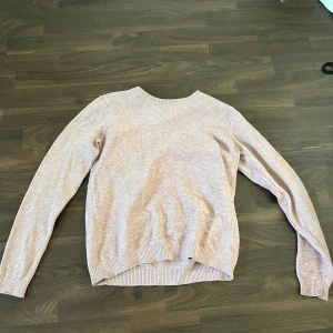 Beige stickad tröja med rund hals - En enkel och stilren beige stickad tröja med rund halsringning och långa ärmar. Tröjan har ribbade muddar vid ärmslut och nederkant, vilket ger en snygg och klassisk look. Perfekt för lager-på-lager under kyliga dagar.