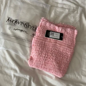 Rosa volangklänning från TwoTwinStyle - Supersöt rosa kortklänning från TwoTwinStyle med smockad överdel och volangig kjol i broderad bomull🩷. Klänningen har en riktigt somrig vibe och är perfekt för dig som gillar romantiska detaljer och pastellfärger. Den är ALDRIG använd!