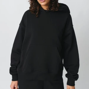 Svart oversized hoodie med huva - En svart oversized hoodie med huva och stor känguruficka framtill. Tröjan har långa ärmar och ribbade muddar vid ärmslut och nederkant. Perfekt för en chill och avslappnad stil.