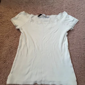Vit offshoulder topp med spets Lager 157 - Supersöt vit offshoulder topp från Lager 157 i storlek XXS. Toppen har korta ärmar och fina spetsdetaljer längs halsringningen och ärmsluten. Perfekt för dig som gillar en feminin och stilren look.