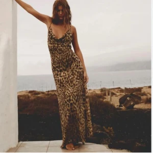 Leopardmönstrad långklänning Zara - Slutsåld, finns inte att köpa längre, Supersnygg långklänning från Zara med leopardmönster och tunna axelband. Klänningen har en lös passform och draperad urringning, perfekt för dig som vill sticka ut. Materialet är lätt och känns svalt mot huden.