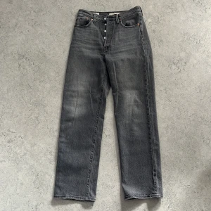 Levi's Ribcage Straight Ankle jeans grå - Grå Levi's Ribcage Straight Ankle jeans med hög midja och raka ben. Klassisk femficksmodell med knappgylf och snygg tvättad finish, även lätt sliten design vid bensluten. Perfekta för dig som gillar en tidlös och avslappnad look.