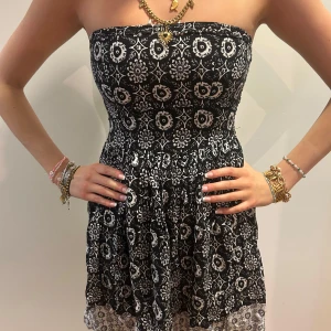 Svartvit blommig tubklänning - Supersöt kort tubklänning i svart och vitt med blommigt mönster och kontrasterande kant nertill. Klänningen har en figurnära överdel och utställd kjol, perfekt för varma dagar. Mjuk och lätt i materialet, riktigt skön att bära. Denna är från barnavdelningen så storleken är barnstorlek XL men storleken motsvarar storlek xs-s💞