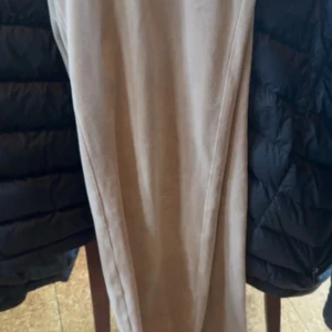 Beiga mjukisbyxor Juicy Couture M - Supermjuka och sköna beiga mjukisbyxor från Juicy Couture i storlek M. Byxorna har en loose passform och är tillverkade i ett lent material som känns lyxigt mot huden. Perfekta för chill dagar eller när du vill vara extra bekväm. Tyvärr saknas bandet i midjan 