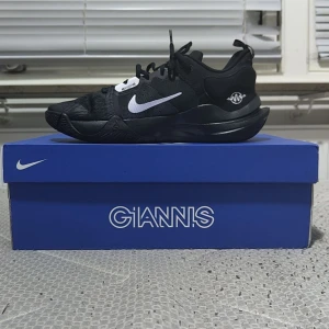 Nike Giannis Immortality Svarta Sneakers - Svarta Nike Giannis Immortality sneakers med vit swoosh och coola vågiga detaljer på sulan. Ovandelen är i mesh och syntet för bra andningsförmåga. Skorna har snörning och en sportig vibe, perfekta för dig som gillar basket eller streetstyle.