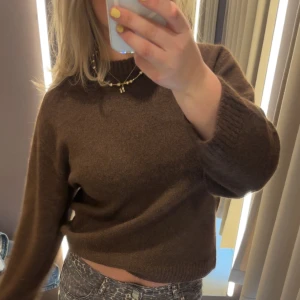 Brun stickad tröja - Mysig brun stickad tröja med rund halsringning och ribbade muddar vid ärmslut och nederkant. Tröjan har en relaxed passform och är perfekt att styla med jeans eller kjol för en chill look.