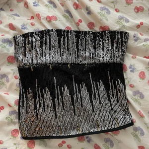 Glittrig svart och silver tubtopp - Säljer en snygg tubtopp med glittriga paljetter i svart och silver. Har sytt själv från en klänning så den är helt unik ⭐️⭐️ vet inte storlek men jag brukar ha 36 ❤️❤️min favorit att ha på fest!! ⚠️OBS bortrest 7juli-4aug, kan annars träffas Stockholm innan 