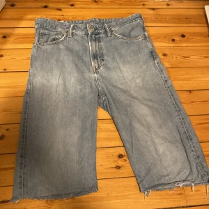 Loose fit jeansshorts/jorts från H&M - Baggy ljusblå jeansshorts/jorts från H&M med loose fit. Klassisk femficksmodell med knapp och dragkedja framtill. Perfekta för en avslappnad streetstil under sommaren.