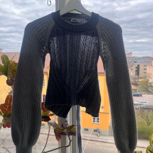Mörkblå stickad tröja från Zara - Säljer en mörkblå stickad tröja från Zara med unik design. Tröjan har långa ärmar och en öppen rygg med knytning. 