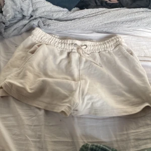 Beige shorts från KappAhl - Säljer ett par bekväma beige shorts från KappAhl. De har en elastisk midja med snörning och är perfekta för en avslappnad stil. Materialet känns mjukt och skönt mot huden.