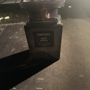 Tom Ford Oud Wood Eau de Parfum 100 ml - Säljer en exklusiv Tom Ford Oud Wood Eau de Parfum i en elegant svart flaska på 100 ml. Doften är känd för sina rika och mystiska noter av oud, vilket ger en lyxig och sofistikerad känsla. Perfekt för den som vill ha en unik och minnesvärd doftupplevelse pris kan diskuteras.