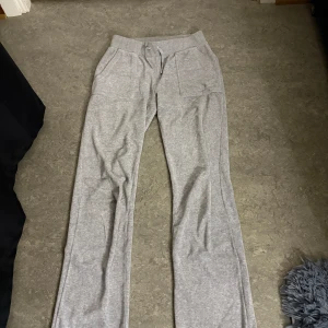 Grå mjukisbyxor från Juicy Couture - Säljer ett par grå mjukisbyxor från Juicy Couture i storlek XS. Byxorna har en bekväm passform med resår i midjan och snörning. Ena metallbiten på snöret har gått av därför lågt pris.