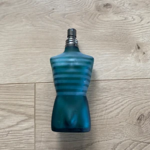 Parfym från Jean Paul Gaultier  - Unik parfymflaska formad som en manlig torso i blått glas med horisontella ränder. Flaskan har en metallisk spraytopp och en stilren design som gör den till en snygg detalj i badrummet.