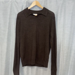 Brun merinoulltröja från These Glory Days - Säljer en stilren brun tröja i merinoull från These Glory Days. Tröjan har en klassisk krage och långa ärmar, perfekt för kyligare dagar. Den är mjuk och bekväm, idealisk för både vardag och mer uppklädda tillfällen.