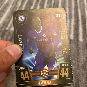 Fotbollskort med spelare i blå tröja - Fotbollskort med en spelare i blå tröja. Kortet har detaljer som 'Defence 44' och 'Attack 44'. Det finns också en logotyp och texten 'Platin Kart'.