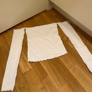 Vit offshoulder topp - Säljer en stilren vit offshoulder topp med långa ärmar. Perfekt för en trendig look. Toppen har en enkel design som gör den lätt att matcha med olika outfits.