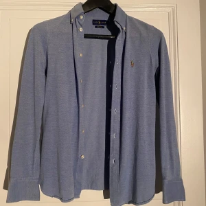 Blå skjorta från Ralph Lauren - Tja! Säljer min ljusblåa skjorta i ett mjukt material, Knit Oxford. Materialet är mjukt är och lite elastiskt. Skjortan är i ett bra skick och passar perfekt till sommaren👍🏼 hör av dig vid eventuella funderingar‼️