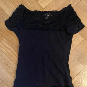 Svart spetsblus - Säljer en elegant svart blus med spetsdetaljer. Blusen har korta ärmar och en vacker spetsdesign vid halsen och ärmarna💓skriv för fler bilder❤️