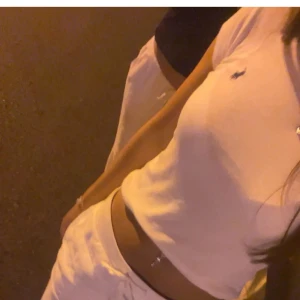 Vit kortärmad topp från Ralph Lauren - Säljer en stilren vit kortärmad topp från Ralph Lauren med en liten broderad logga på bröstet. Perfekt för en avslappnad och snygg look.Helt ny