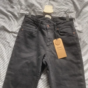 Svarta Bootcut jeansbyxor från Lindex - Snygga svarta jeansbyxor från Lindex med klassisk femficksdesign och knappgylf. Byxorna har en bootcut passform och är perfekta för en stilren look. De är tillverkade i ett bekvämt material som passar till många olika tillfällen.