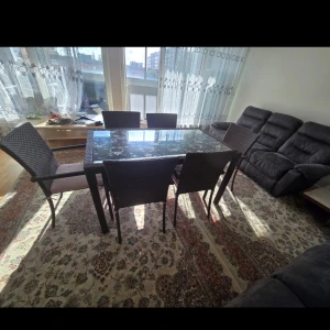 Matbord med glasbordsskiva och stolar - Elegant matbord med glasbordsskiva och fyra stolar i flätad design. Bordet har en modern stil och passar perfekt i ett ljust vardagsrum. Stolarna har en bekväm sits och ryggstöd, vilket gör dem idealiska för långa middagar.