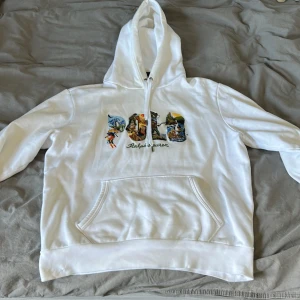 Vit hoodie från Ralph Lauren - Säljer en snygg och ovanlig vit hoodie från Ralph Lauren med färgglatt broderat mönster på bröstet. Perfekt för en avslappnad stil!