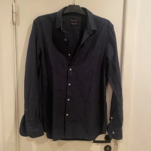 Mörkblå skjorta från Massimo Dutti - Snygg mörkblå skjorta från Massimo Dutti med klassisk krage och vita knappar. Perfekt för en stilren look. Tillverkad av fint tyg för en bekväm känsla. Passar L perfekt