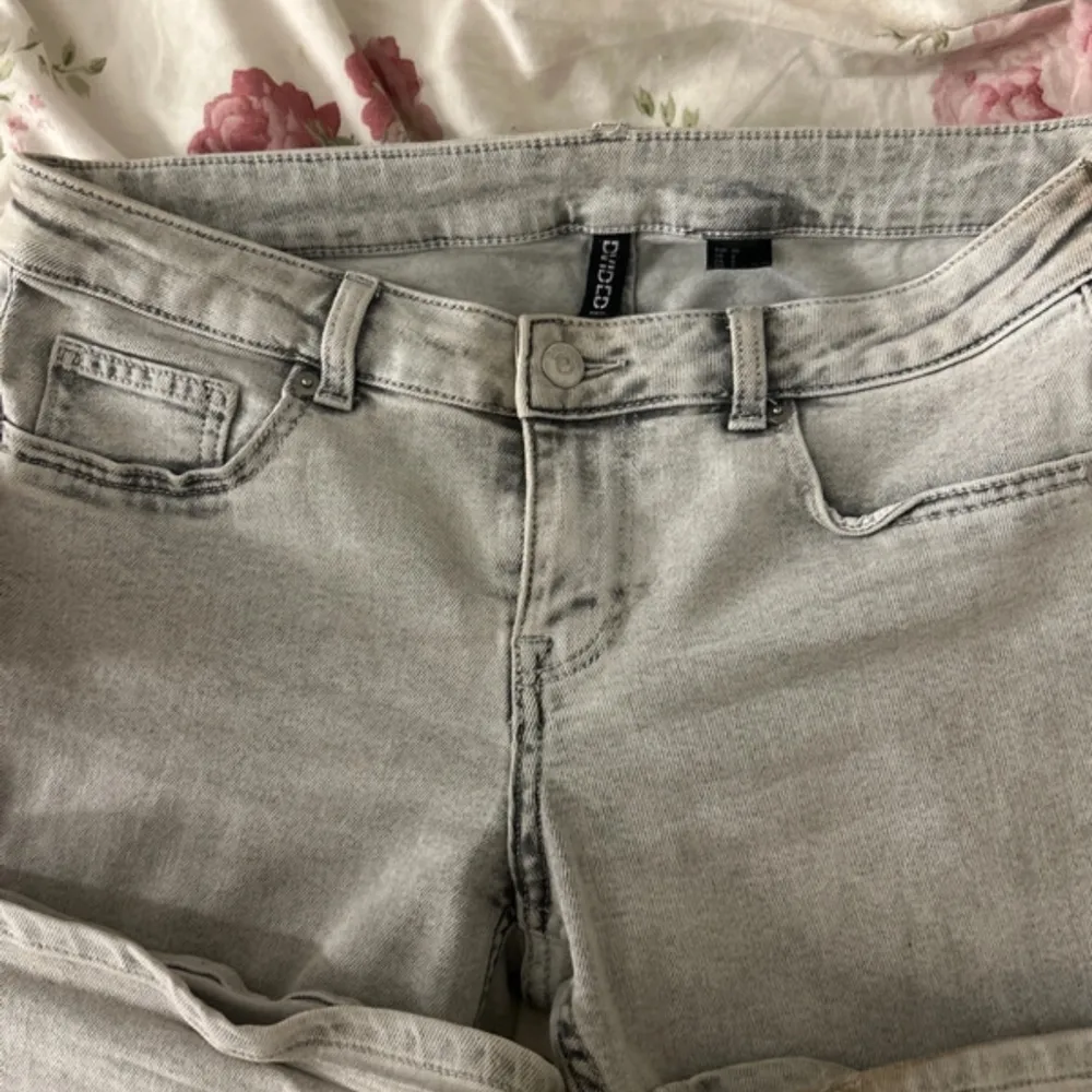 Snygga grå jeansbyxor från Gina Tricot i storlek 40. De har en klassisk femficksdesign och en knappgylf. Perfekta för en stilren look.. Farkut & Housut.
